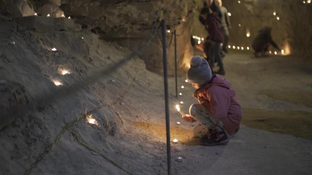 Pige tænder lys ved lysfest i Thingbæk kalkminer