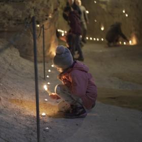 Pige tænder lys ved lysfest i Thingbæk kalkminer